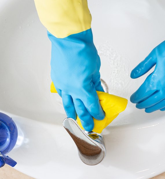 Hands with gloves cleaning a bathroom